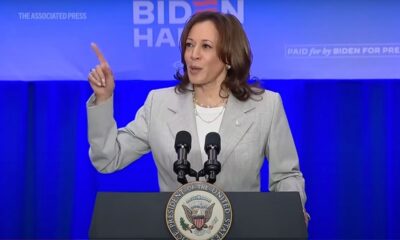 woman at a podium pointing her finger in the air